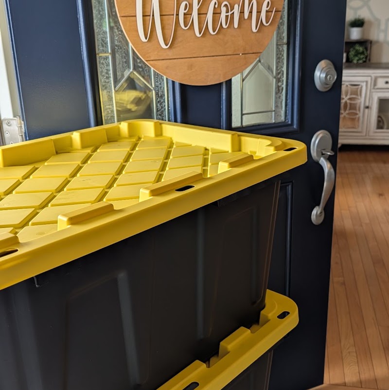 Close-up of yellow-lidded moving totes stacked in an open doorway